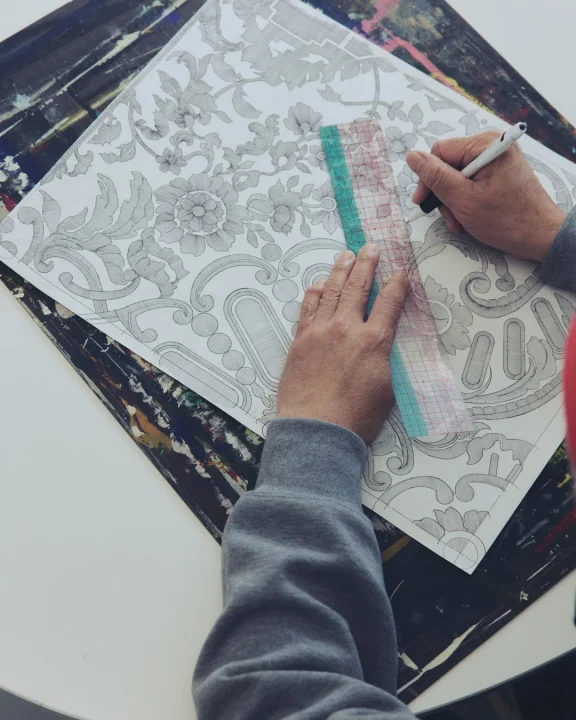 紙に花と装飾のパターンを描く手元