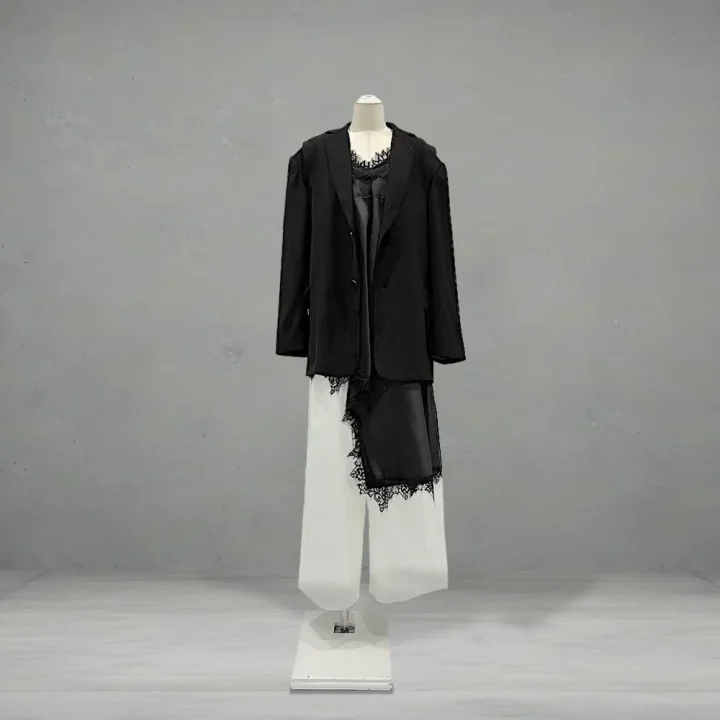 黒いブレザー、レース付きの黒いトップス、白いワイドパンツを着用したマネキンの全身ショット