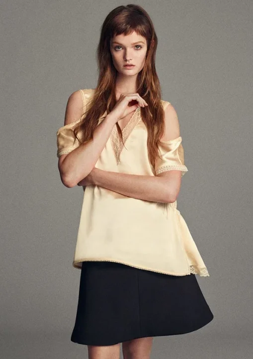 オフショルダーのベージュサテントップスとミニスカート