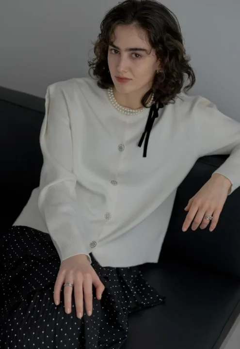 白いカーディガンとドット柄のスカートを着用した女性