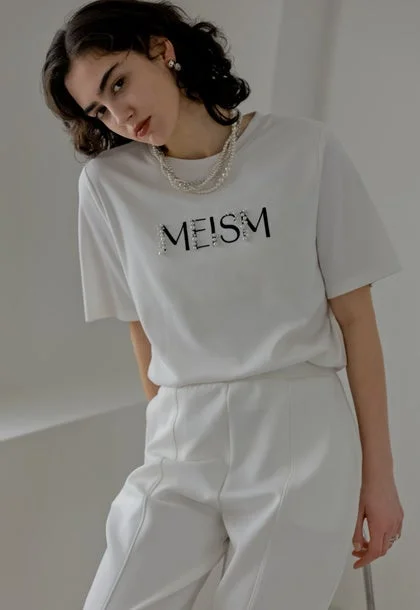 白いTシャツと白いパンツ、パールネックレスの女性