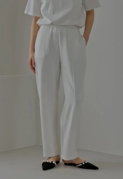 白いTシャツと白いパンツ、パール飾りの黒いフラットシューズ