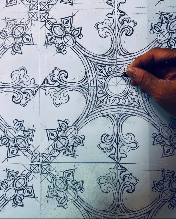 紙の上に複雑で対称的な装飾模様を手描きする様子