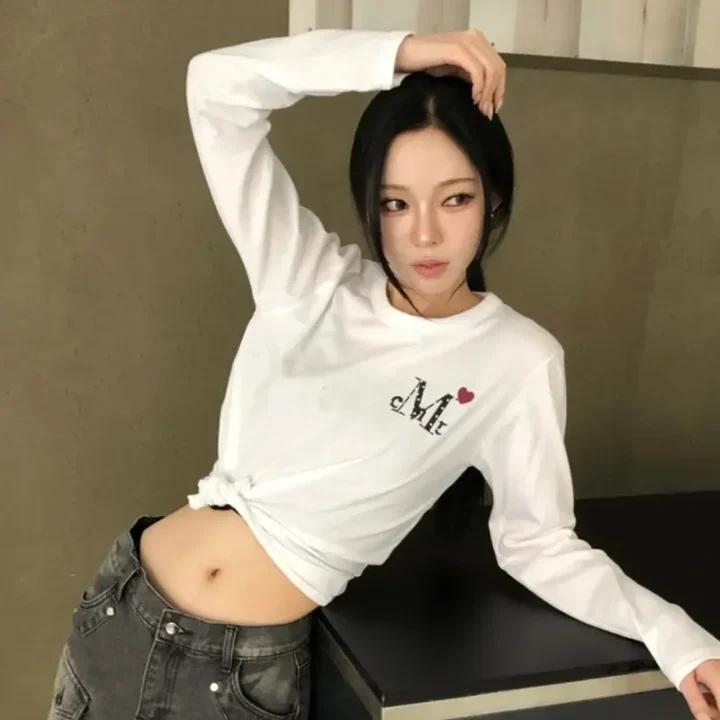 白い長袖クロップトップとジーンズを着用した若い女性