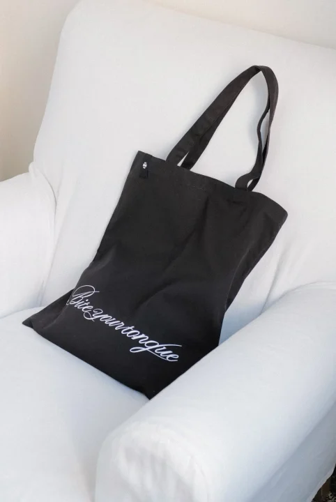 白いアームチェアに置かれた黒いトートバッグ