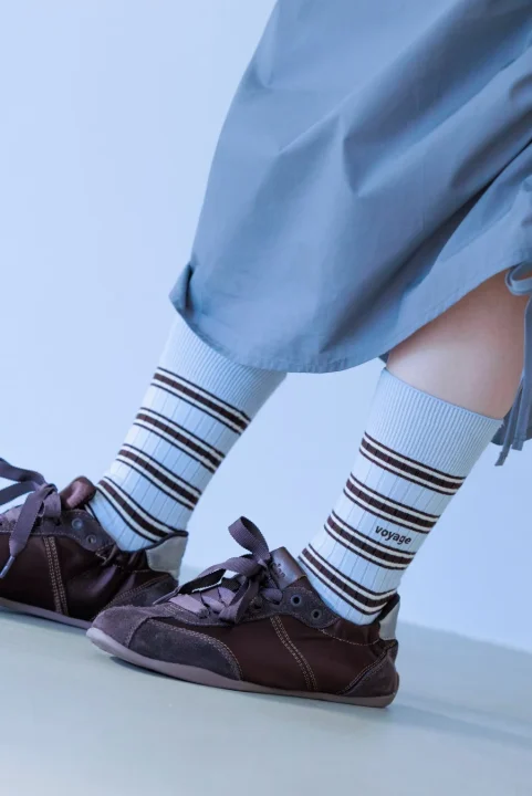 ライトブルーのスカートにストライプ柄ソックスとブラウンのスニーカー