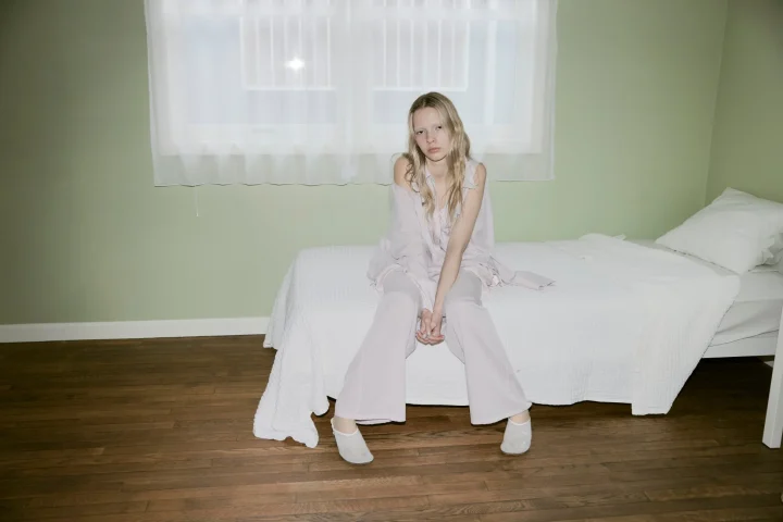 白いベッドに座る女性のポートレート