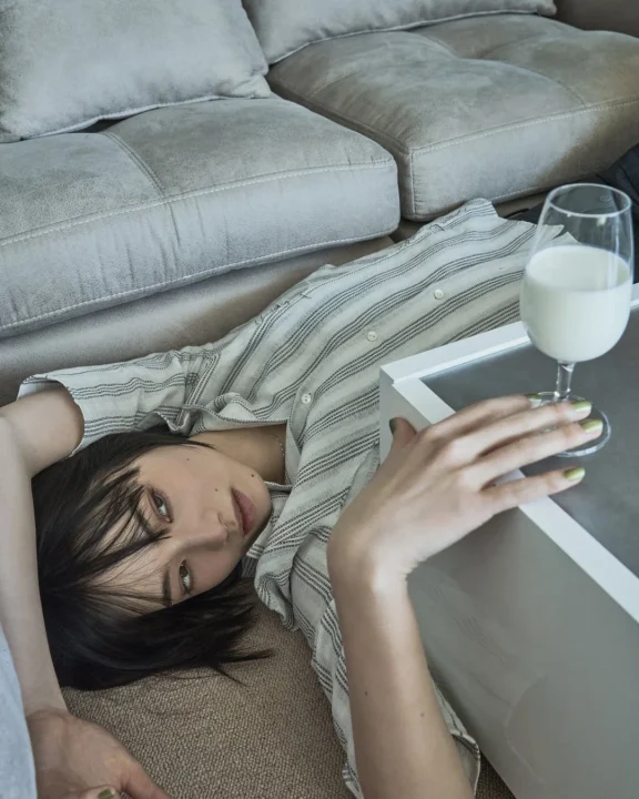 ソファの横の床に横たわりストライプシャツを着た小松菜奈さん