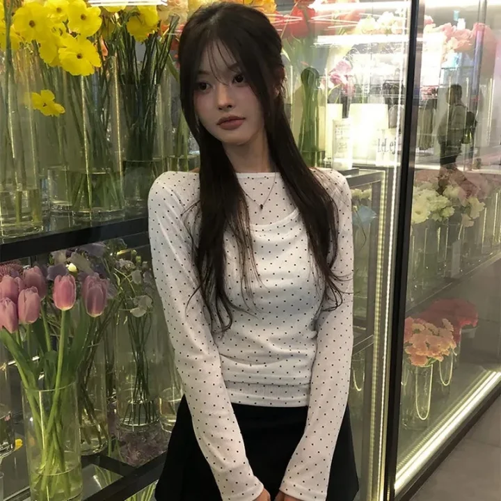 ポルカドット柄の白いトップスと黒いスカートを着た女性