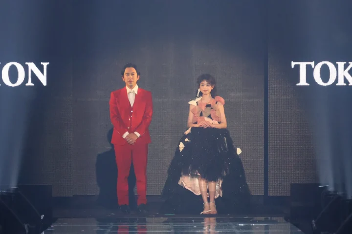 リボンを連ねたドレスを着たモデルと登壇者