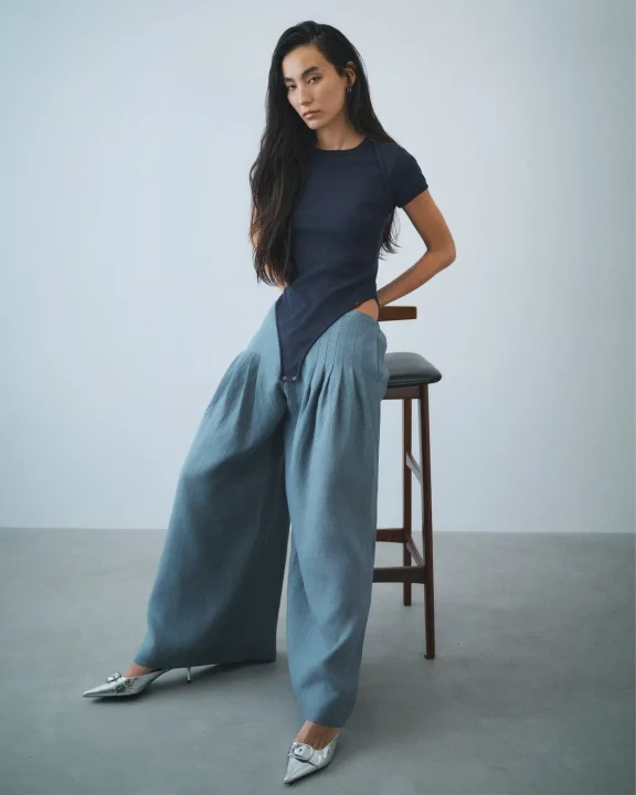 アシンメトリートップスとワイドパンツを着用した女性