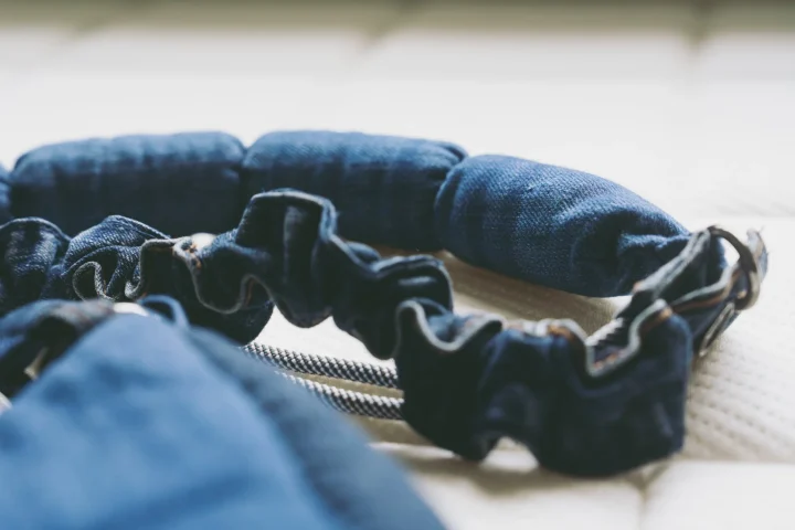 デニム生地で作られた複数の円筒状のパーツと、フリル状の生地が連なったアイテムのクローズアップ。背景には白いテクスチャの布が見える。