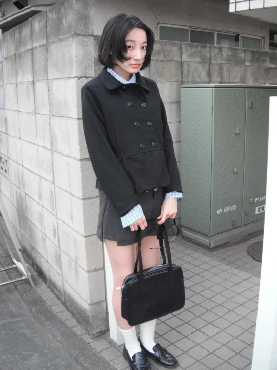 ショートヘアの若い女性が街中で立っている