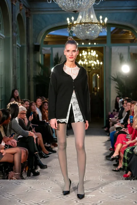 黒いカーディガンと白いレースのインナー、グレーのタイツを着用したモデル