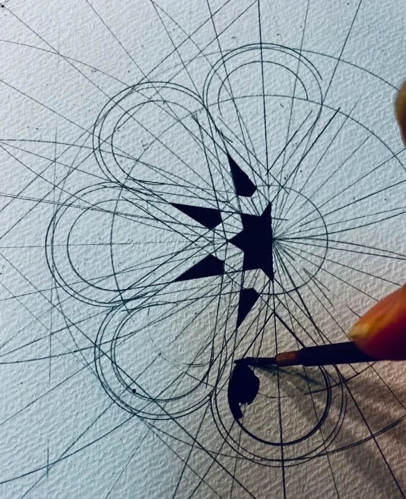 複雑な幾何学模様に筆で一部を黒く塗りつぶす手元