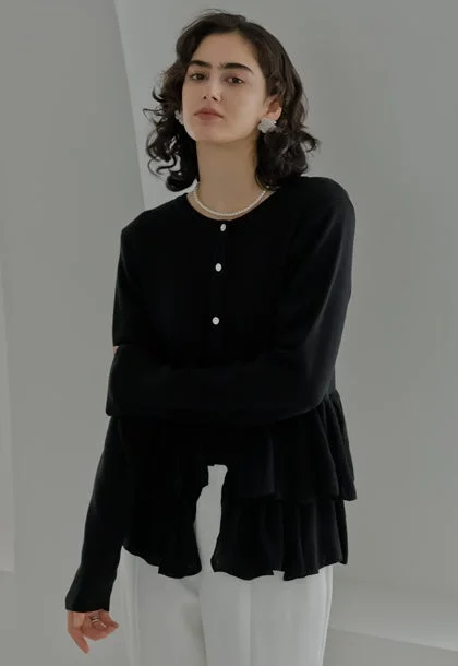 黒いティアードデザインのカーディガンと白いパンツ