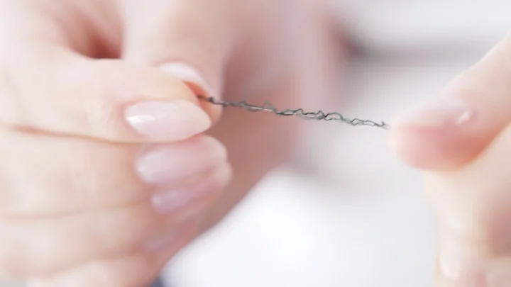 指でつまむ糸のクローズアップ