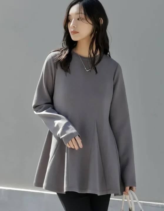 グレーのペプラムトップスと黒いパンツ