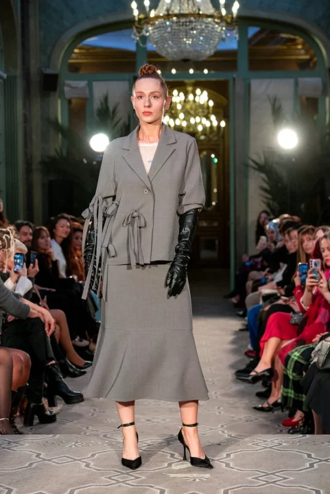 グレーのスーツに黒いロンググローブとハイヒールを合わせたモデル