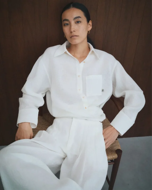 白いリネンシャツとワイドパンツを着用した女性