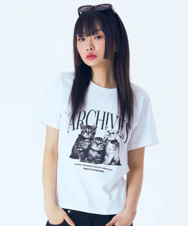 猫のプリントと「ARCHIVES」の文字が入った白いTシャツを着た若い女性