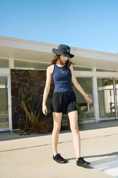 ネイビーのタンクトップと黒のショートパンツを着用し、ハットをかぶった女性