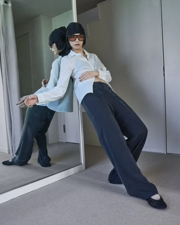 白いシャツと黒いパンツ、ヘッドスカーフとサングラスを着用し鏡にもたれかかる小松菜奈さん