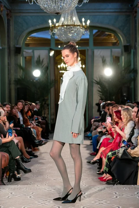 ライトグレーのドレスと白いフリル襟の衣装を身につけたモデル