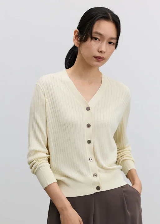 アイボリーのリブVネックカーディガンとブラウンのパンツ