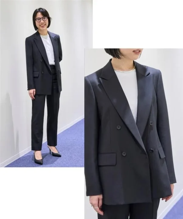 黒のダブルブレストジャケットとパンツのセットアップを着用した女性