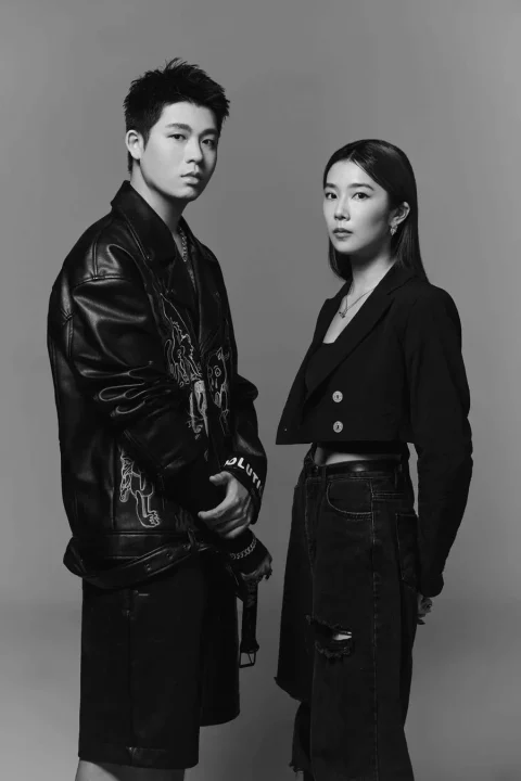 モノクロのスタジオでポーズをとる男女のポートレート。男性はレザージャケット、女性はクロップドジャケットとダメージジーンズを着用し、クールな雰囲気を醸し出している。