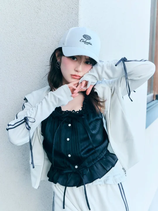 白いキャップをかぶり、白と黒のスポーティカジュアルな服装の若い女性