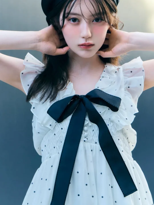 黒いベレー帽をかぶり、白地に黒いドット柄のワンピースを着た若い女性