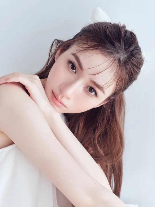 白いトップスを着て腕を抱えるようなポーズの女性