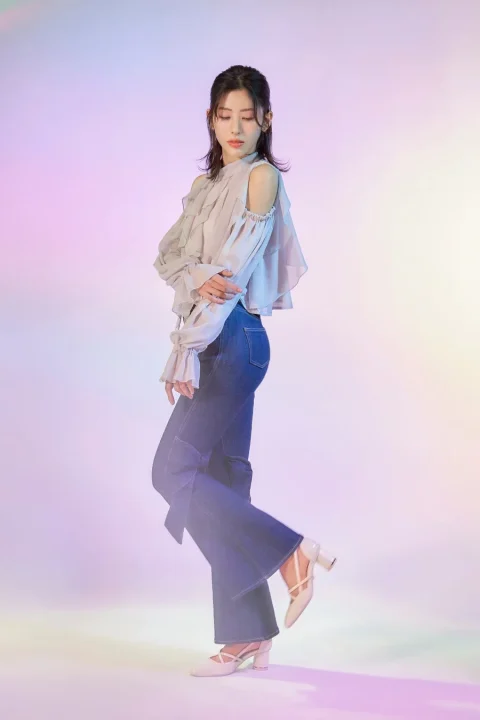 オフショルダーブラウスとフレアジーンズの女性