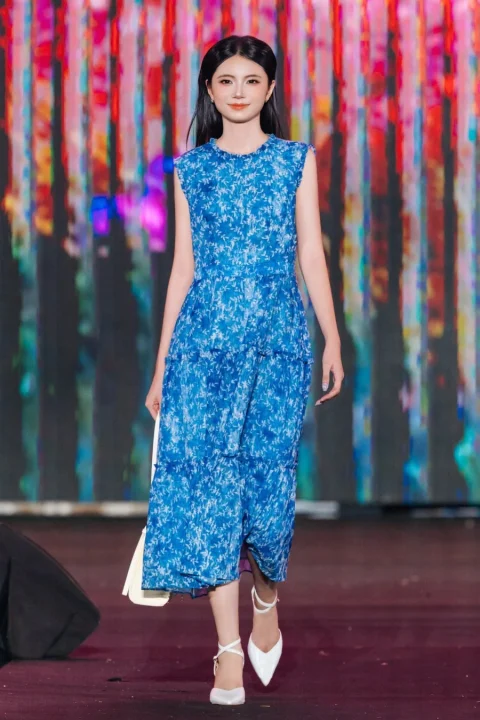 青い花柄のティアードドレスを着用しランウェイを歩くモデル