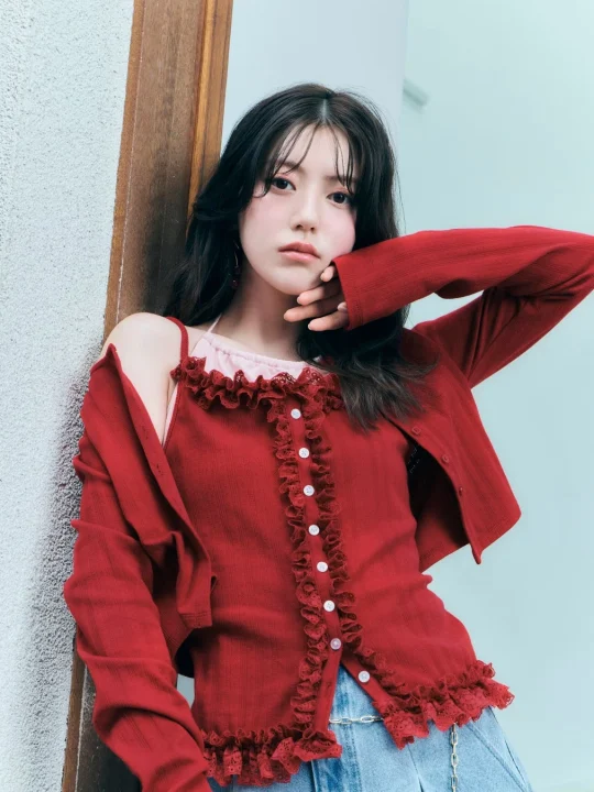 赤いフリル付きトップスとカーディガンを着用した若い女性