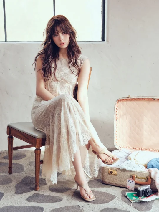 ベージュのレースワンピースを着た女性が椅子に座っている画像