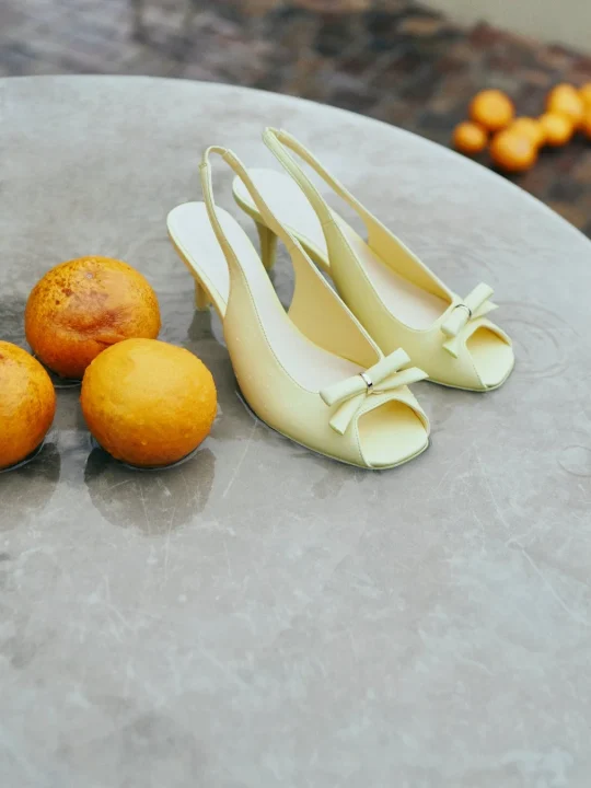 淡い黄色のリボン付きパンプスと、水滴のついたオレンジ