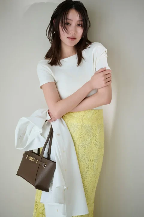 白トップスとイエローレーススカート、シャツを腕に