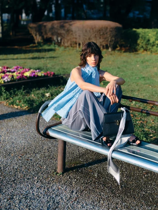 水色のトップスとグレーのワイドパンツを着用した女性