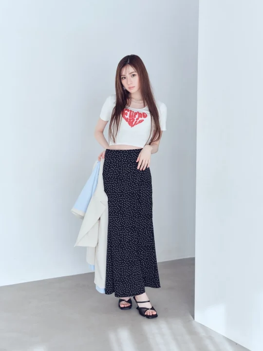 白いクロップトップと黒いドット柄ロングスカートを着用した女性