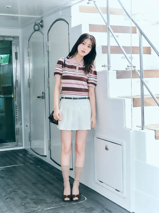 ボーダー柄のポロシャツと白いプリーツミニスカートを着用した若い女性