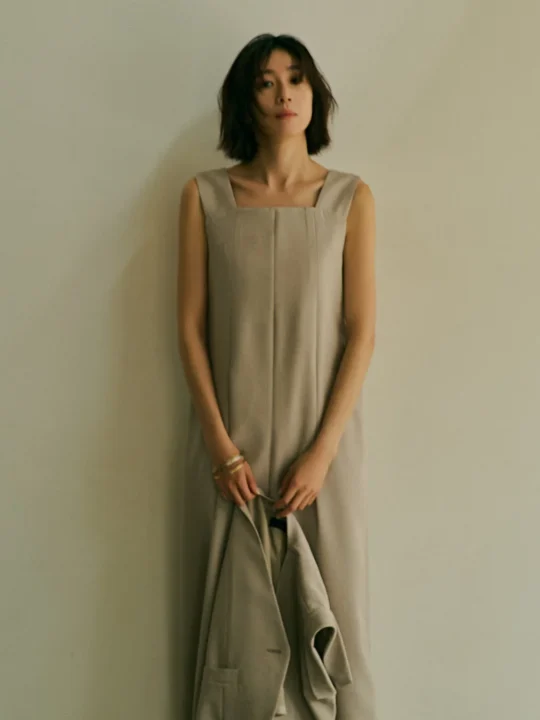 ベージュのワンピースとジャケットを持つ女性