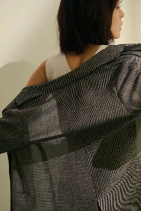 ストライプジャケットを羽織ろうとする女性の後ろ姿