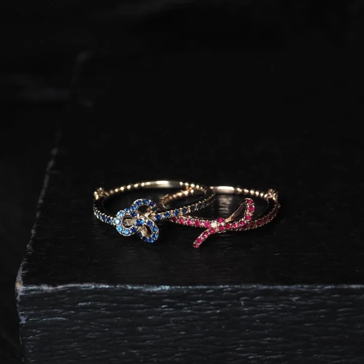 青と赤の宝石が散りばめられた結び目デザインのリング
