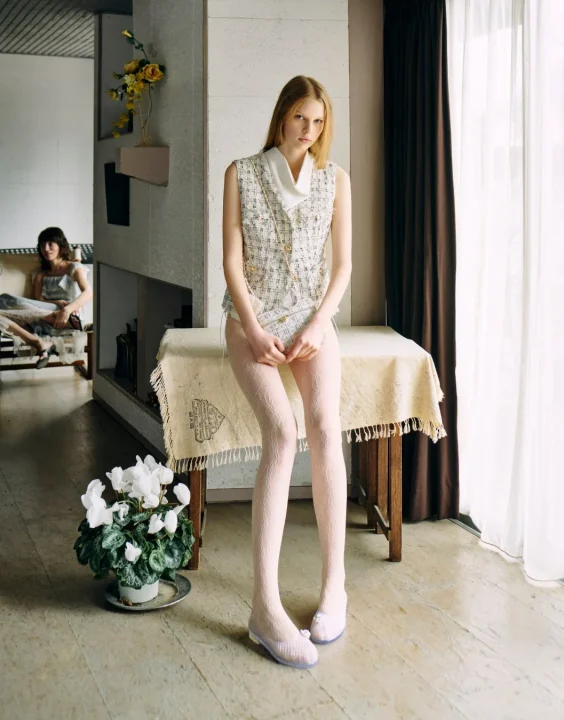 ツイード風のベストと透かし柄のタイツを着用したモデル