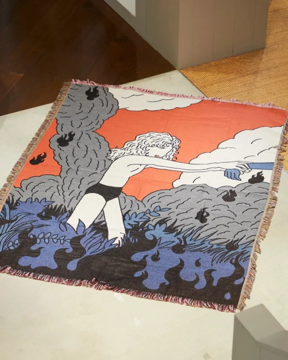 炎の中で消火活動をする女性のイラストが描かれたブランケット