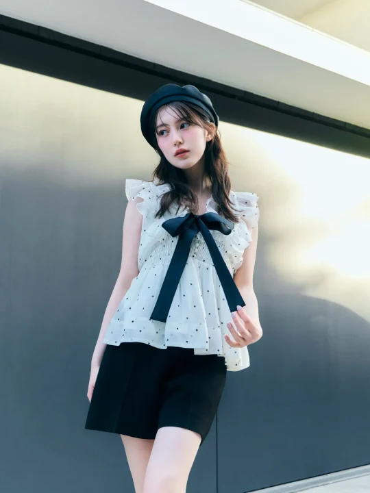 ベレー帽とドット柄のトップス、黒いショートパンツを着用した女性