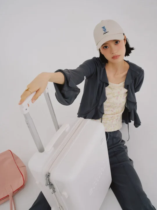 スーツケースに手を置く女性